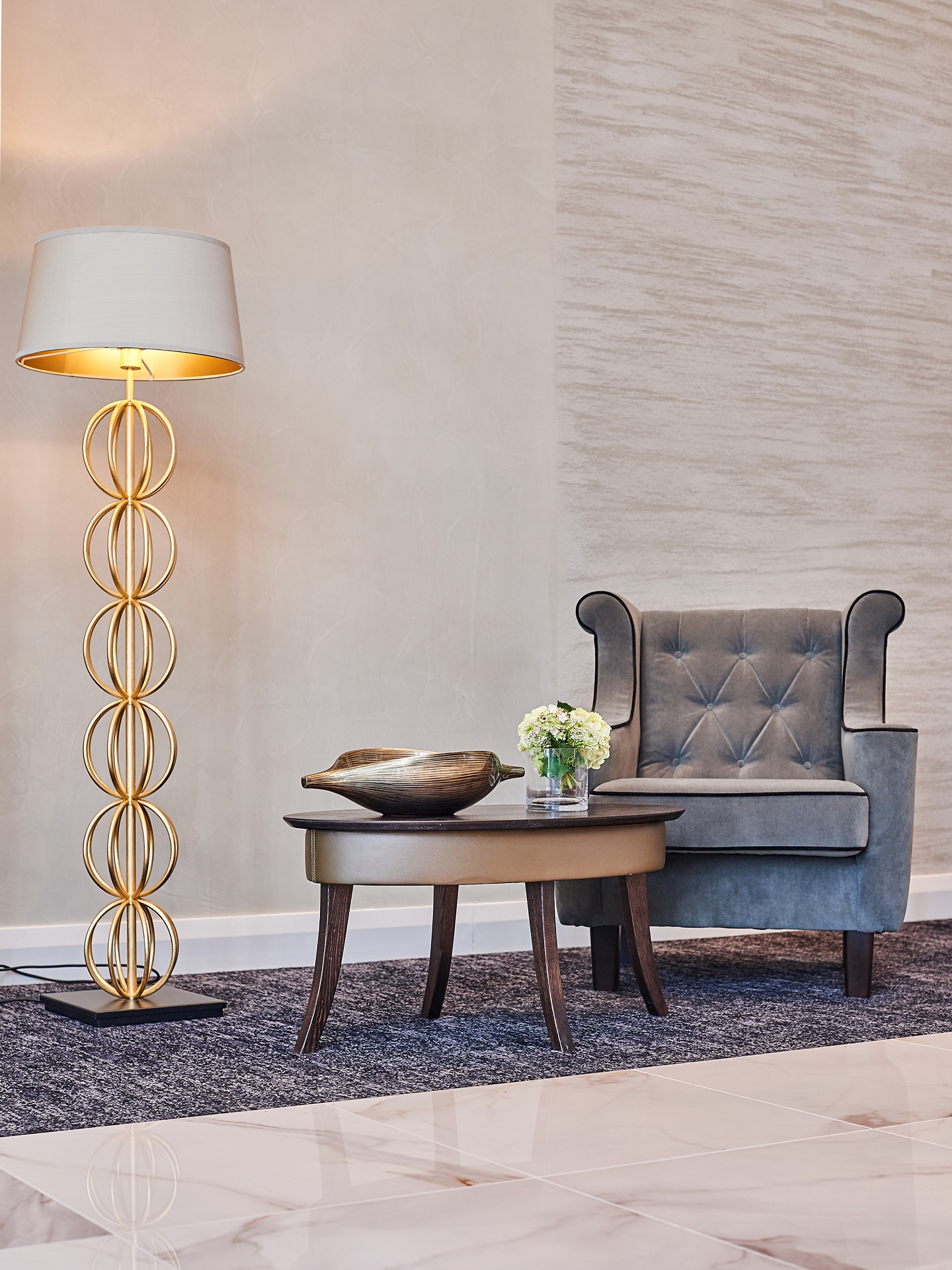 Corner of luxury room with chair, table and gold lamp using Armourcoat Travertine and Smooth Polished Plaster finishes on wall